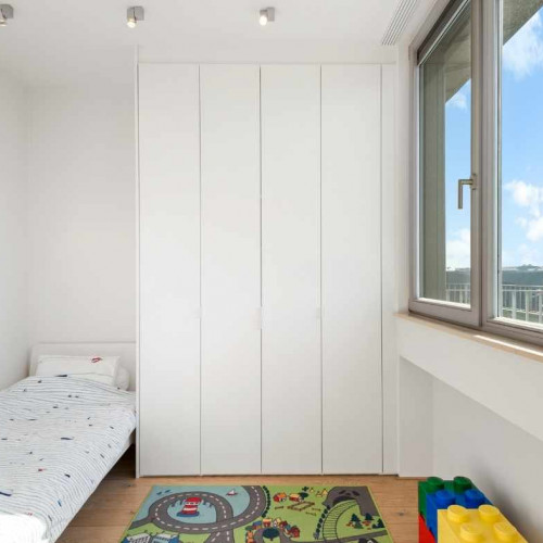 Ook de kinderkamer kan je voorzien voor maatwerk. Zo houden onze interieuradviseurs bij het ontwerp er rekening mee dat alle spulletjes van zoon- of dochterlief netjes een plekje kunnen krijgen en dat de kast mee kan groeien eens je kind ouder wordt.  Deze klant koos voor een strakke kamershoge slaapkamerkast . Door de witte, greeploze uitvoering, loopt de slaapkamerkast naadloos over in de kamer.