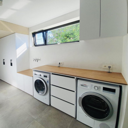 Voor deze klant realiseerden we een praktische wasplaats. Zo worden die huishoudelijke taken een stuk aangenamer.  De klant koos voor alpine witte kasten, voorzien van matzwarte trekkers. Er werd ruimte voorzien voor wasmachine en droogkast.  Boven de lage kasten werd een kerselaar blad geplaatst. Dit geeft ruim voldoende plek om de was uit te sorteren.