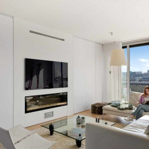 Deze klanten klopten bij ons aan om voldoende opbergruimte te creëeren in de leefruimte . Links en rechts van de uitspringende nis, waarin open haard en tv verwerkt zitten, integreerden we daarom kamershoge wandkasten . Doordat onze interieuradviseur aanraadde om te kiezen voor greeploze witte maatkasten, voorzien van tip-on systeem,  loopt het geheel mooi over in de rest van de kamer. 