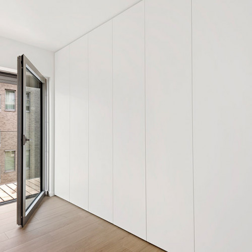 Een slaapkamer moet rust uitstralen in al zijn eenvoud. Dat was het motto van onze klanten. Zo kwamen we samen tot dit strakke ontwerp.  We plaatsten een kamershoge kastenwand over de volledige breedte van de slaapkamer. De kasten zijn voorzien van. greeploze draaideuren met push to open systeem. In de kasten is zowel hangruimte als legvlakken voorzien.